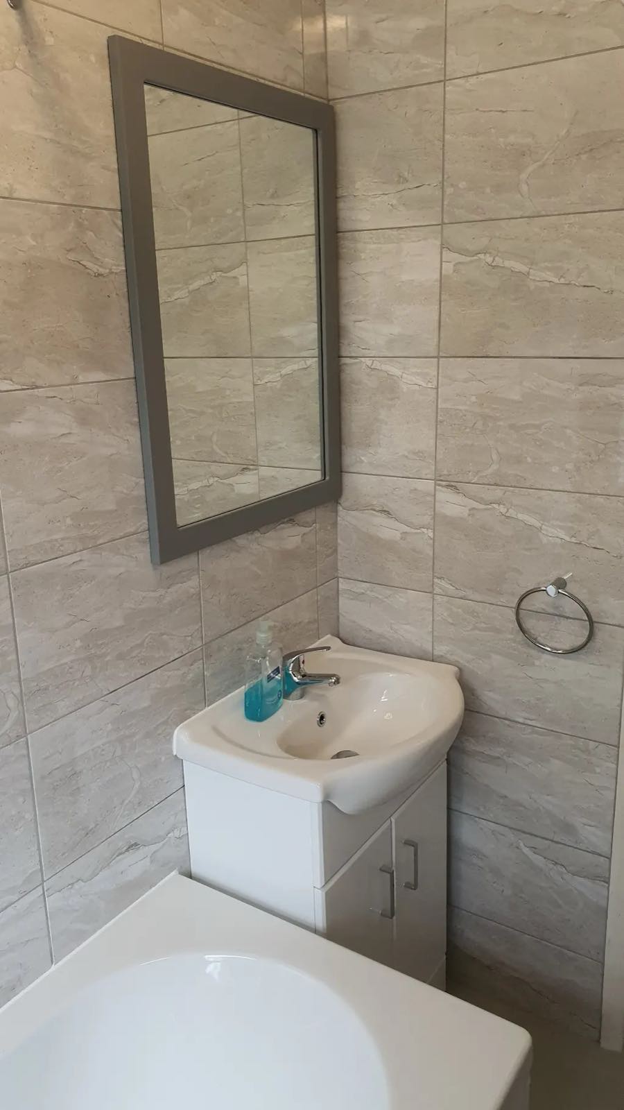 After: the refitted wall with stone-effect tiles, vanity basin and framed mirror by ATR Kitchens and Bathrooms
