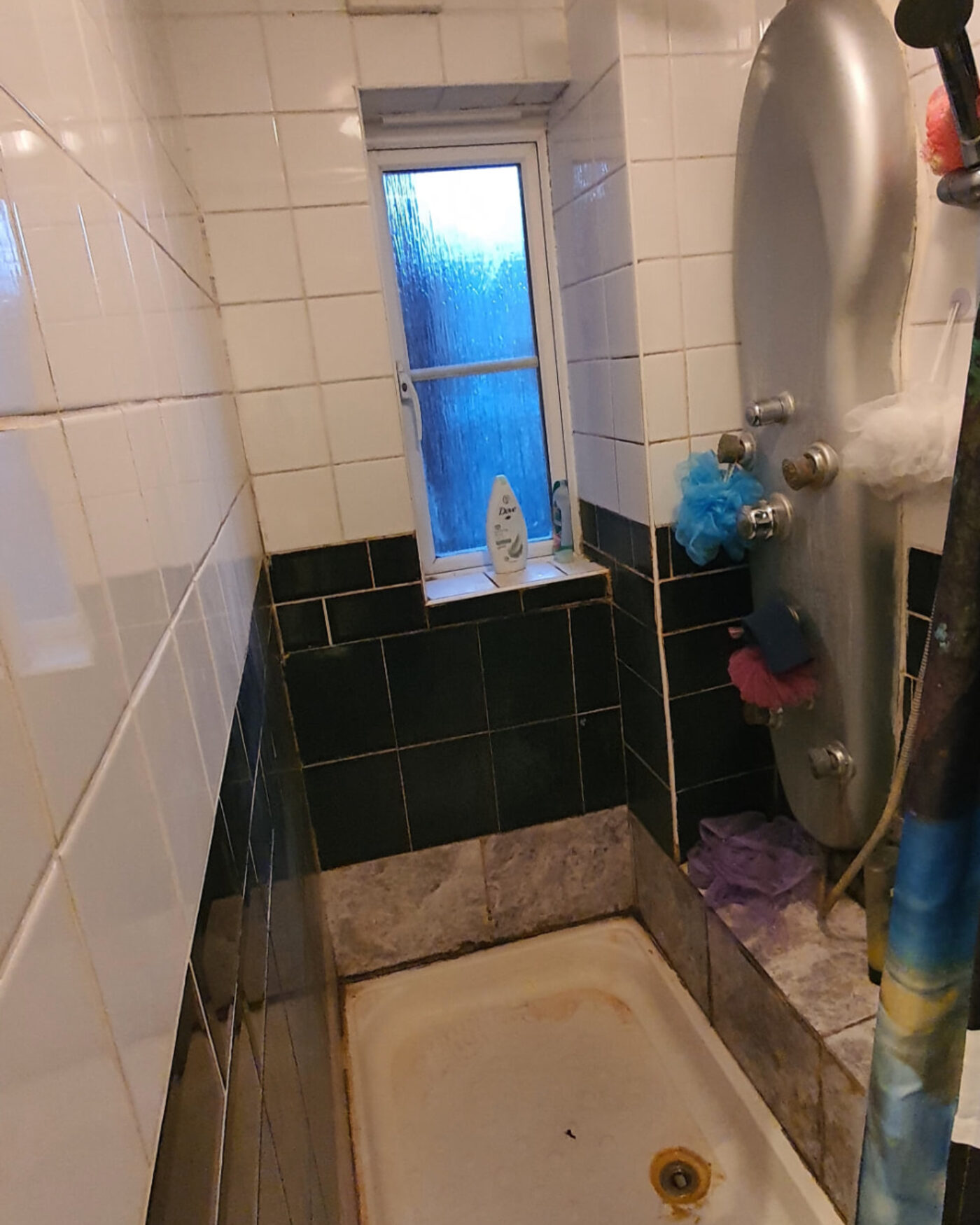 Before: the old narrow en-suite with dated white and dark green wall tiles and a worn shower tray