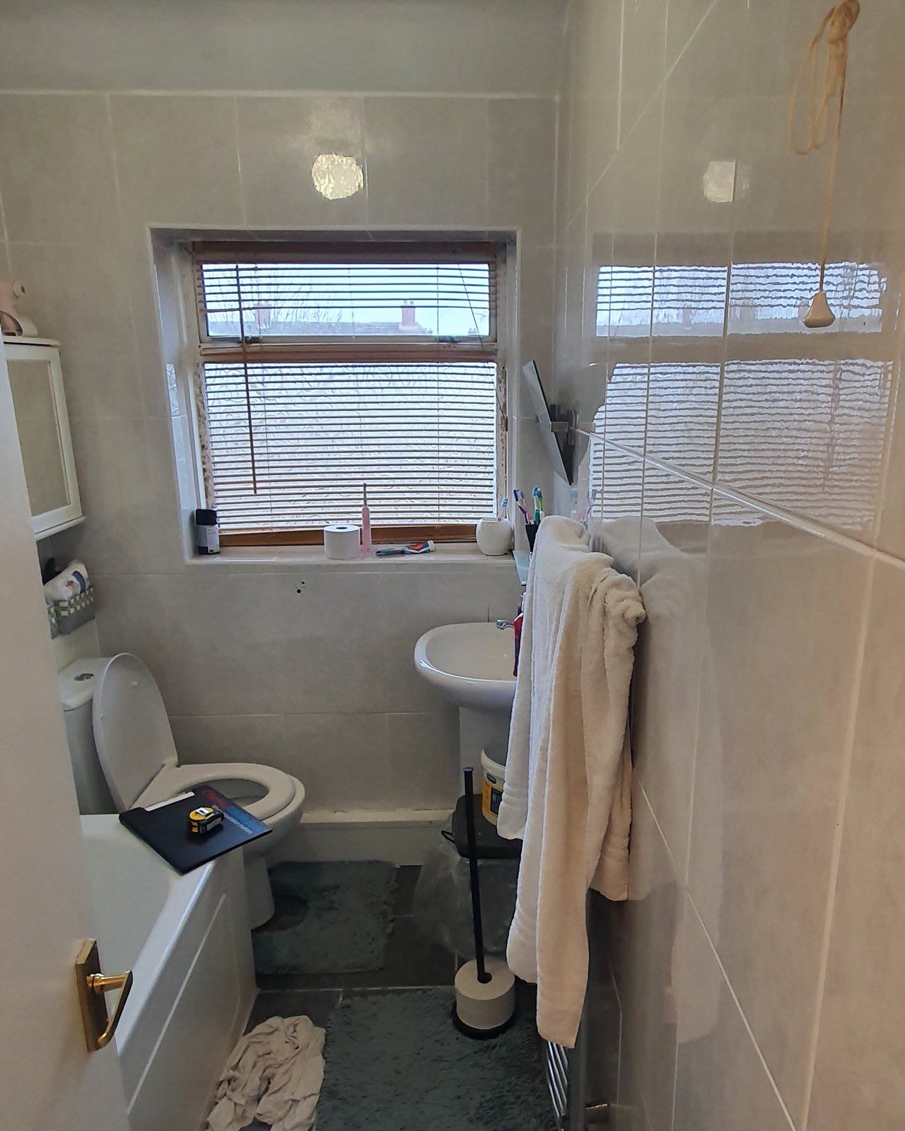 Before: the old bathroom with plain white tiles and a pedestal basin