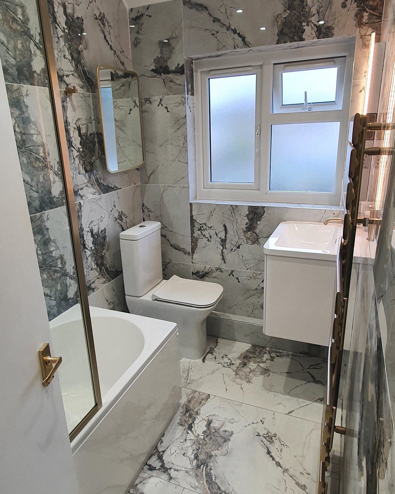 After: the same bathroom finished in marble-effect tiles with a wall-hung vanity and gold fittings by ATR Kitchens and Bathrooms