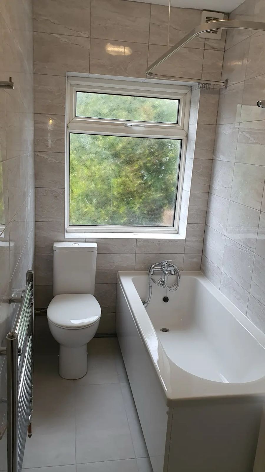 After: the same bathroom with new white suite, grey tiling and a fresh floor by ATR Kitchens and Bathrooms