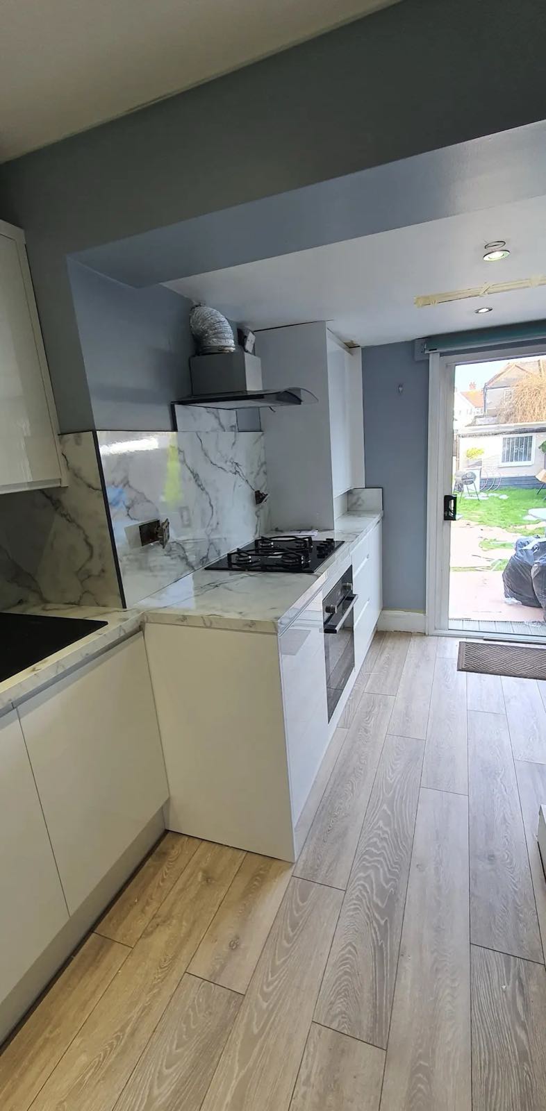 After: the new open-plan kitchen with white units, marble splashback and the garden doors by ATR Kitchens and Bathrooms