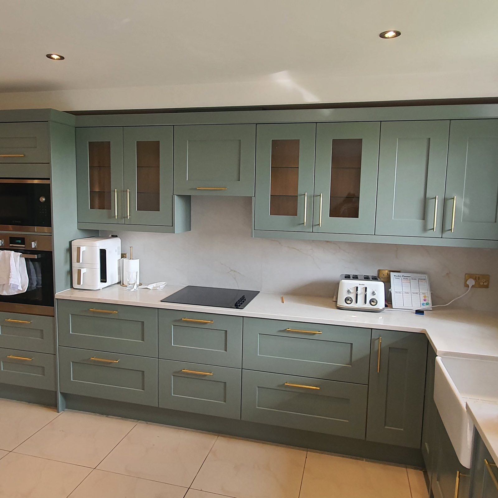 After: the finished sage green shaker kitchen with white worktops and tiled splashback by ATR Kitchens and Bathrooms