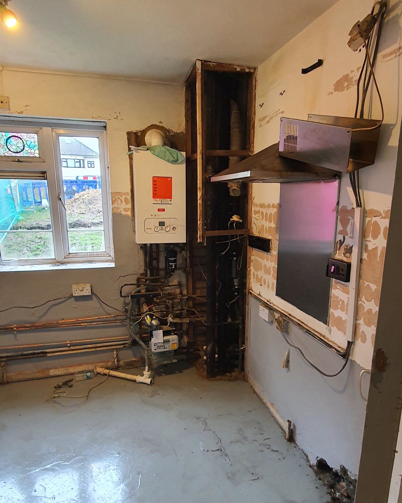Before: the room stripped back to bare walls with the old boiler and pipework exposed