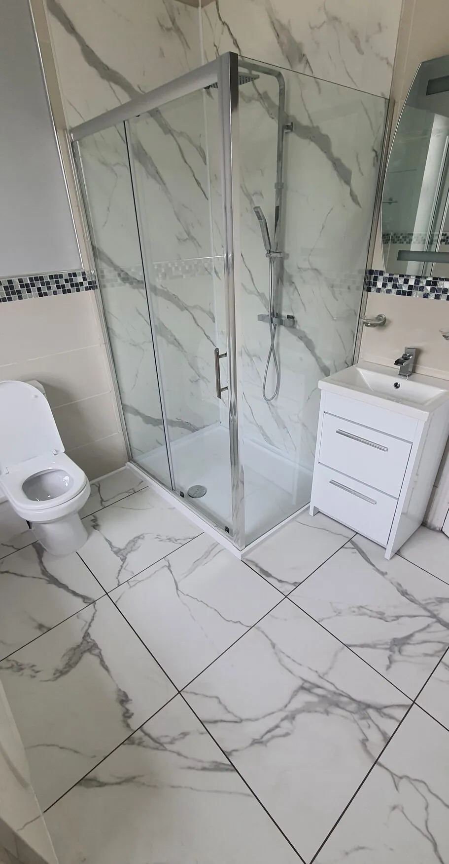 Shower room reinstated after an insurance repair, with marble-effect tiles, a corner shower and a white vanity unit