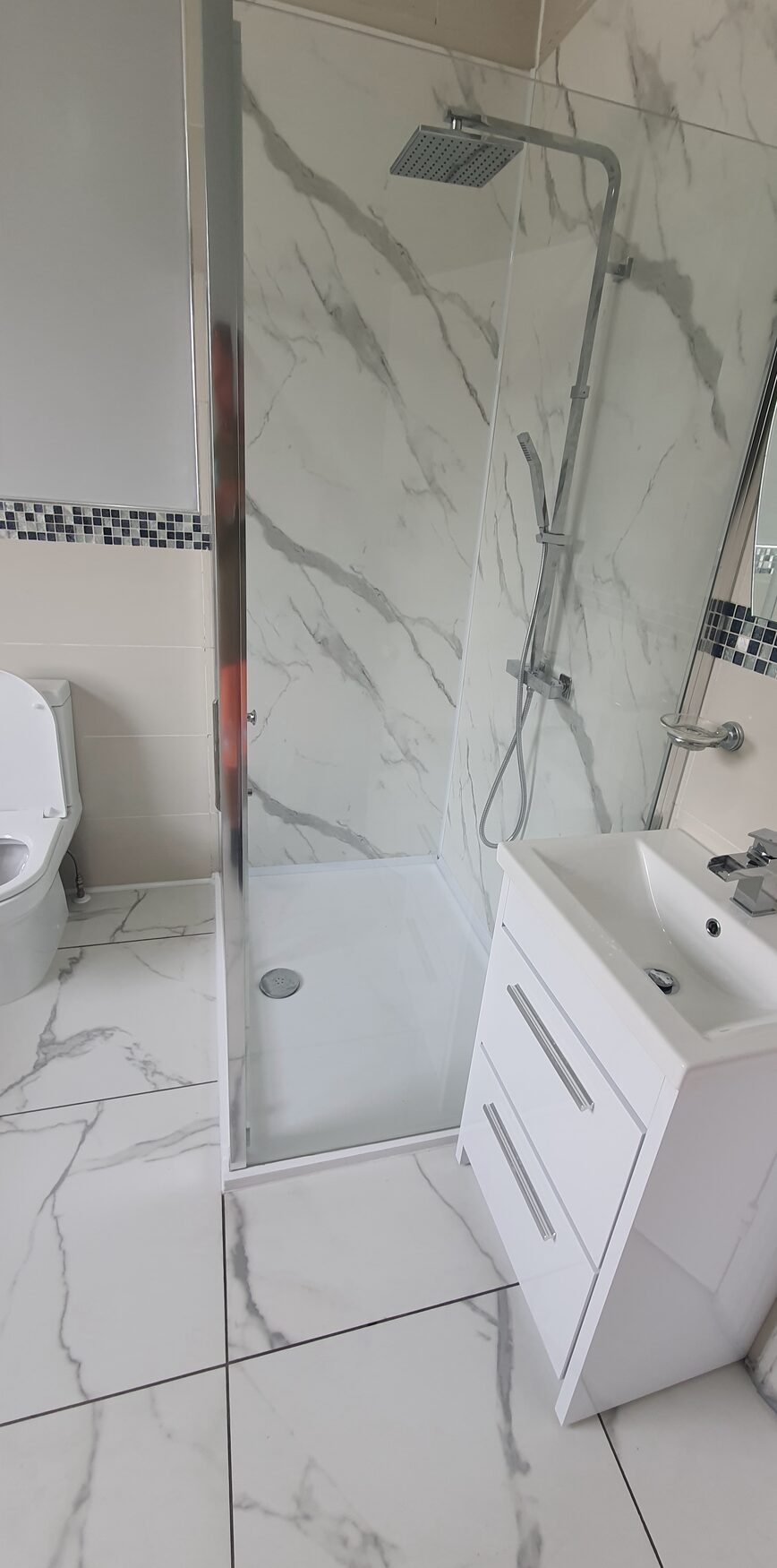 Insurance repair shower and vanity unit in marble-effect tiling by ATR Kitchens and Bathrooms in Grays